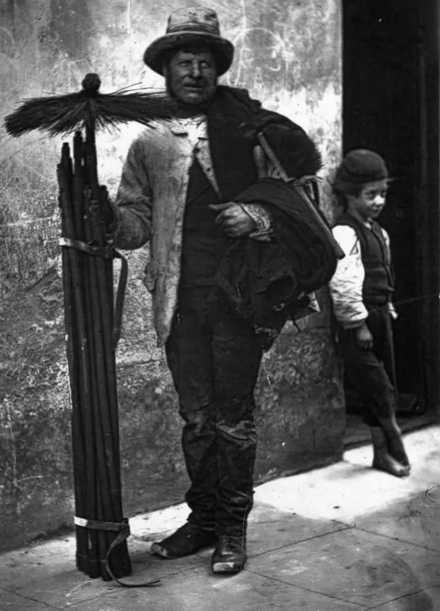 Chimney Sweep and His Apprentice: A glimpse into 1877 reveals a chimney sweep hard at work, accompanied by his young assistant.